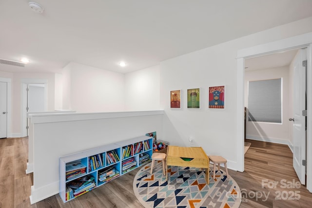 recreation room with visible vents, baseboards, and wood finished floors