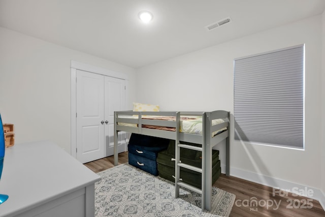 bedroom with a closet, visible vents, and wood finished floors