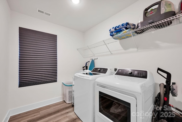 laundry room featuring laundry area, visible vents, baseboards, light wood-style floors, and washing machine and clothes dryer