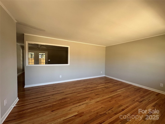 spare room featuring baseboards, dark wood-style flooring, and crown molding