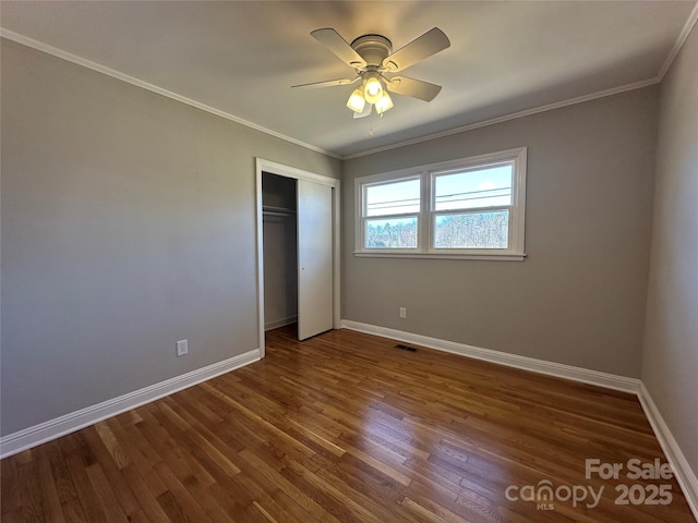 unfurnished bedroom with ornamental molding, dark wood-style flooring, visible vents, and baseboards