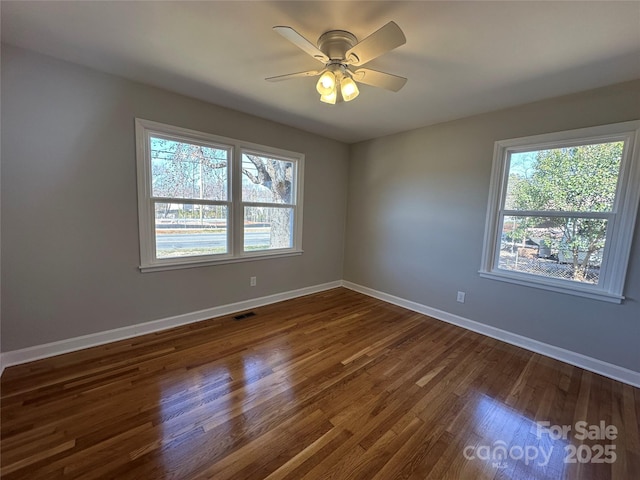 unfurnished room featuring dark wood-type flooring, visible vents, ceiling fan, and baseboards