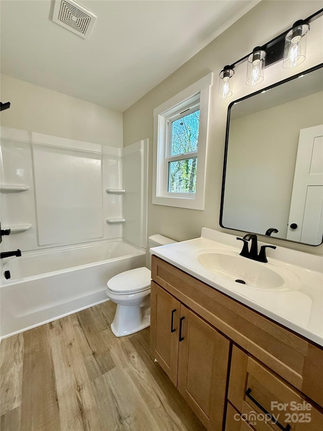 bathroom featuring visible vents, toilet, wood finished floors, bathtub / shower combination, and vanity