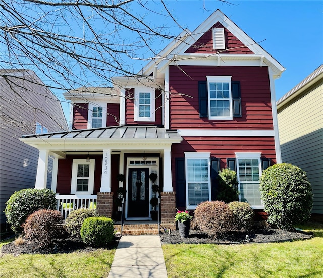 craftsman-style home with metal roof, brick siding, covered porch, and a standing seam roof