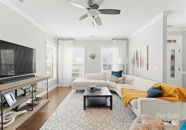 living area with crown molding, wood finished floors, and a wealth of natural light