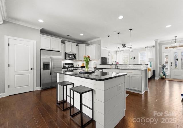 kitchen with a center island, ornamental molding, appliances with stainless steel finishes, a peninsula, and a sink