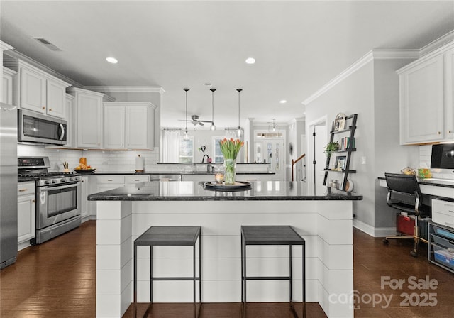 kitchen with decorative backsplash, a kitchen breakfast bar, ornamental molding, and stainless steel appliances