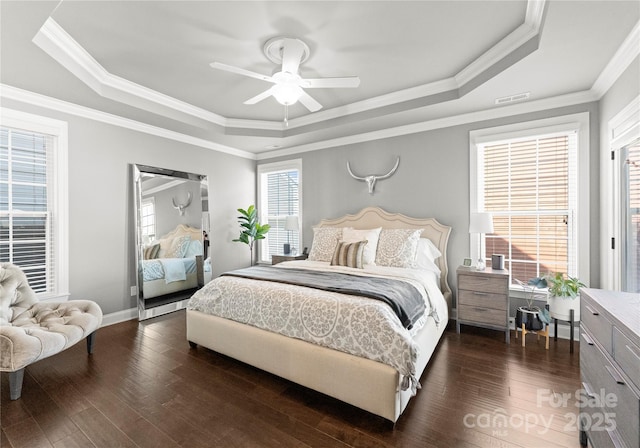 bedroom with a tray ceiling, visible vents, and dark wood-type flooring