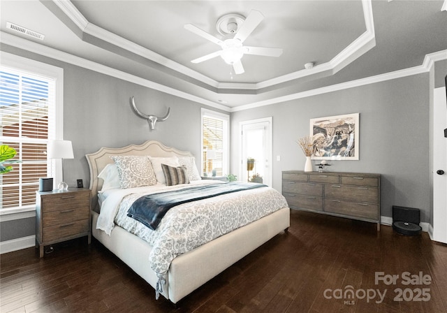 bedroom with visible vents, a raised ceiling, multiple windows, and dark wood finished floors