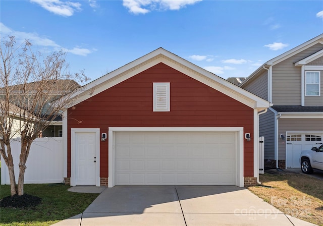 view of front facade featuring concrete driveway, an attached garage, and fence