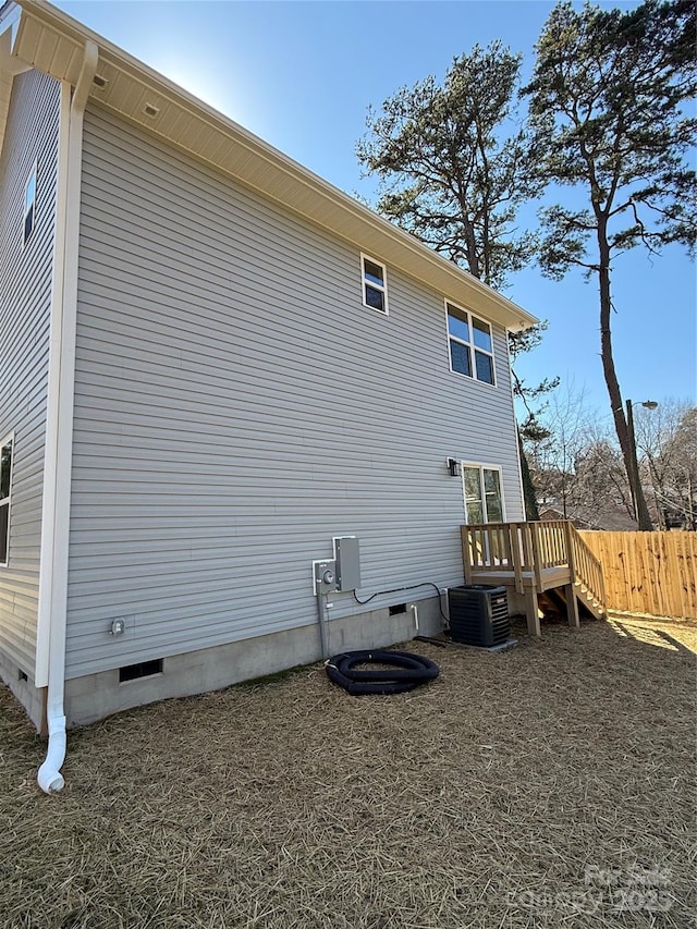 view of side of home with crawl space, central AC, fence, and a deck