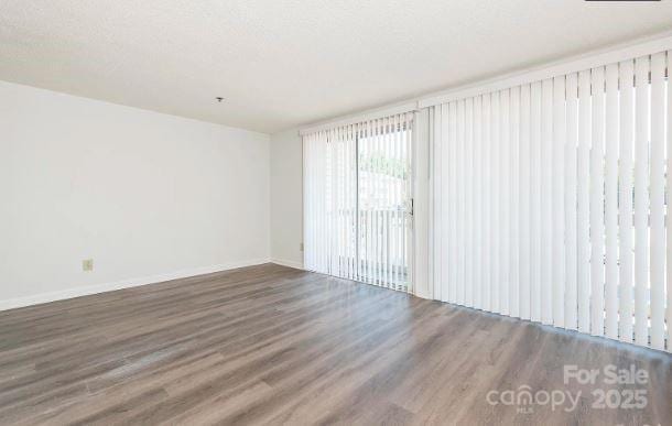 empty room with baseboards and dark wood-style flooring