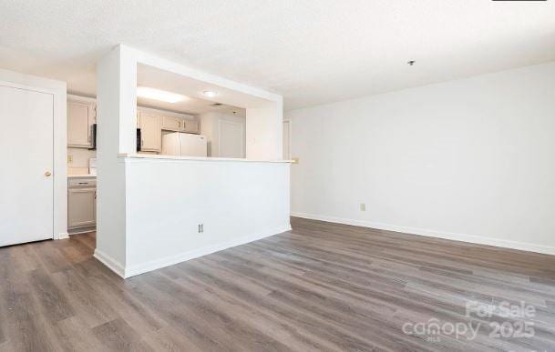 unfurnished living room featuring baseboards and dark wood-style flooring