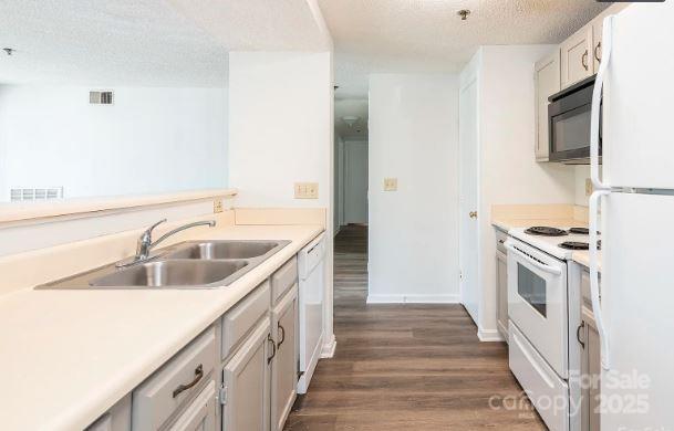 kitchen featuring white appliances, visible vents, light countertops, and a sink