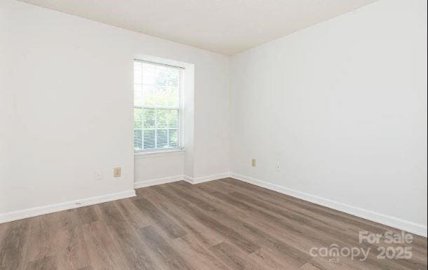 unfurnished room with dark wood-style floors and baseboards