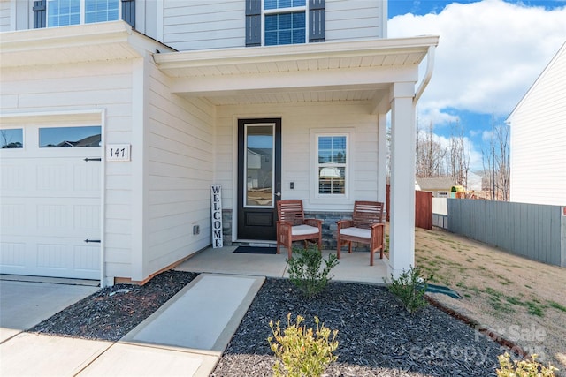 doorway to property featuring a garage, fence, and a porch