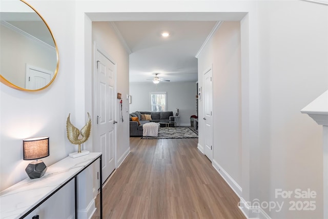 corridor with baseboards, ornamental molding, and wood finished floors