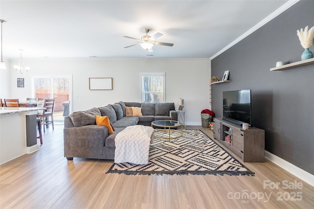 living area featuring plenty of natural light, ornamental molding, light wood-style flooring, and baseboards