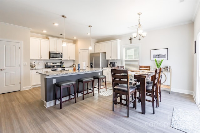 dining space with baseboards, ornamental molding, a notable chandelier, and light wood-style floors