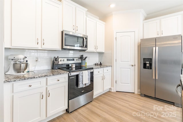 kitchen featuring stainless steel appliances, light wood-style floors, ornamental molding, white cabinetry, and light stone countertops