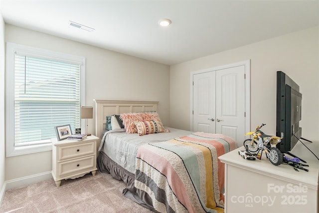 bedroom with a closet, visible vents, and light carpet