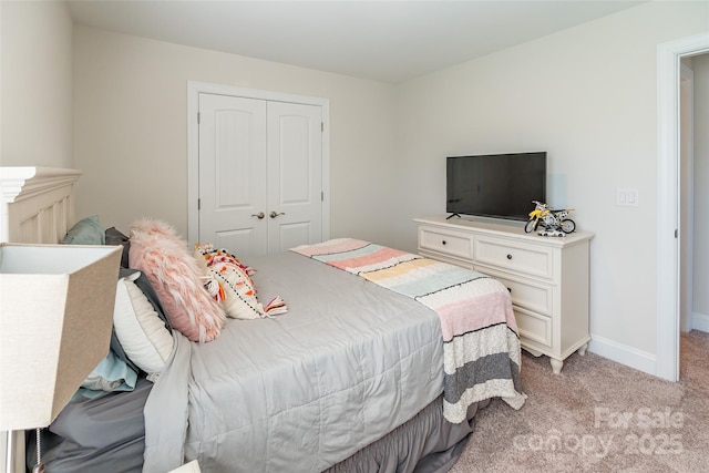 bedroom with baseboards, a closet, and light colored carpet