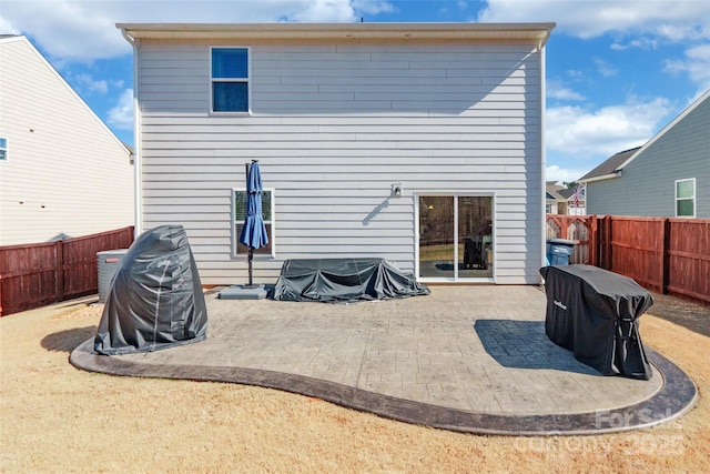 rear view of house with a fenced backyard and a patio