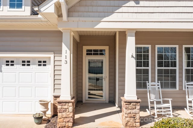 view of exterior entry featuring a garage and covered porch