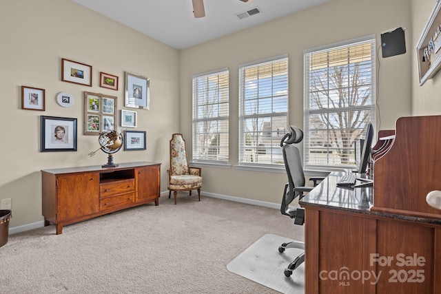 office space featuring ceiling fan, visible vents, baseboards, and light colored carpet