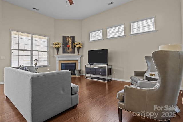 living room featuring baseboards, visible vents, dark wood-style flooring, and a glass covered fireplace