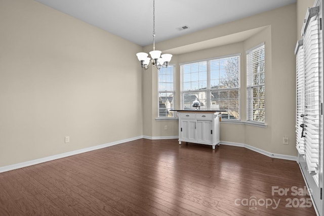 unfurnished dining area with baseboards, dark wood-type flooring, visible vents, and an inviting chandelier