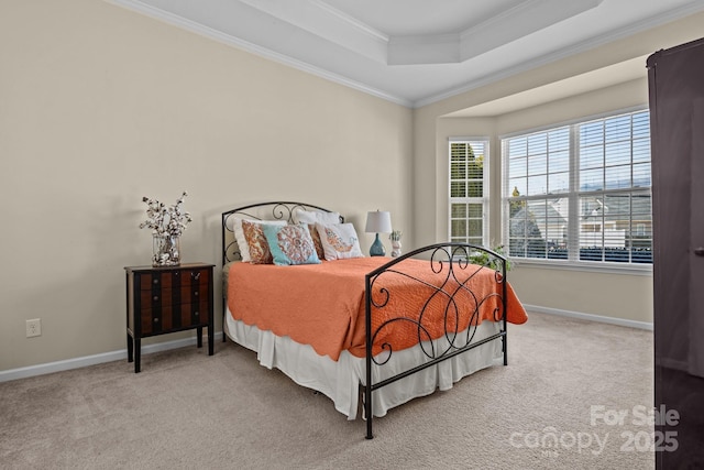 carpeted bedroom with ornamental molding, a tray ceiling, and baseboards