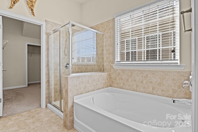 full bath featuring a garden tub, a stall shower, a walk in closet, and tile patterned floors