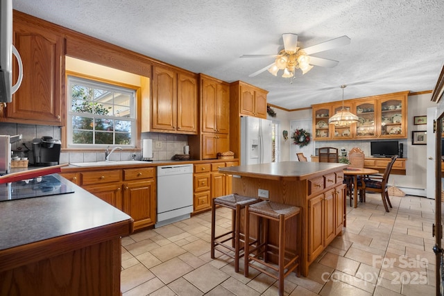 kitchen with white appliances, brown cabinetry, and tasteful backsplash