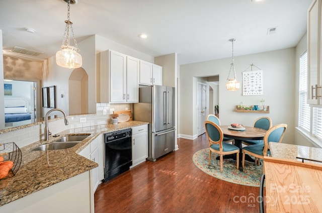 kitchen with light stone counters, arched walkways, high quality fridge, a sink, and dishwasher