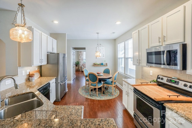 kitchen featuring dark wood-style flooring, a sink, white cabinetry, baseboards, and appliances with stainless steel finishes