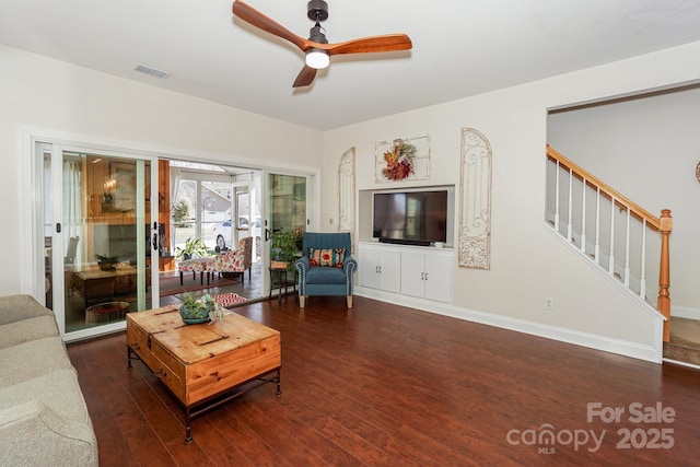 living area with hardwood / wood-style flooring, a ceiling fan, baseboards, visible vents, and stairway