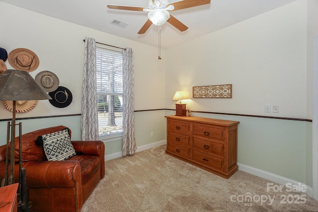 living area with light carpet, ceiling fan, visible vents, and baseboards