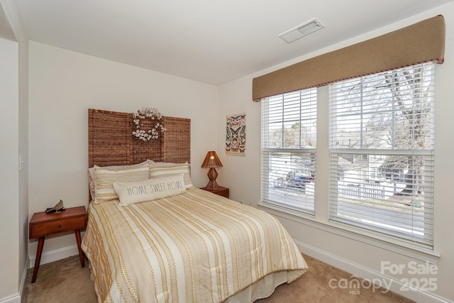 bedroom with light carpet, visible vents, and baseboards