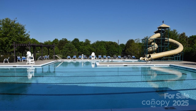 pool with a patio area, a pergola, and a water slide