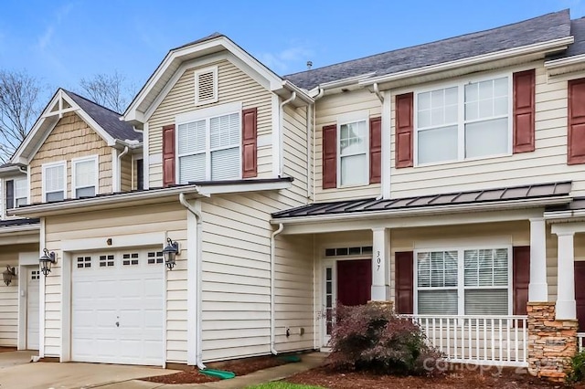 multi unit property featuring an attached garage, a standing seam roof, driveway, and metal roof