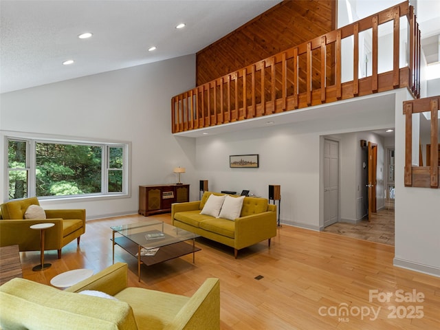 living area featuring light wood-type flooring, baseboards, and high vaulted ceiling