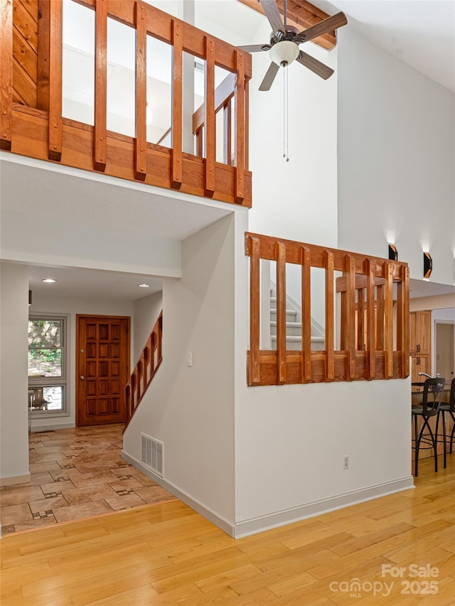 stairs featuring a high ceiling, visible vents, baseboards, and wood finished floors