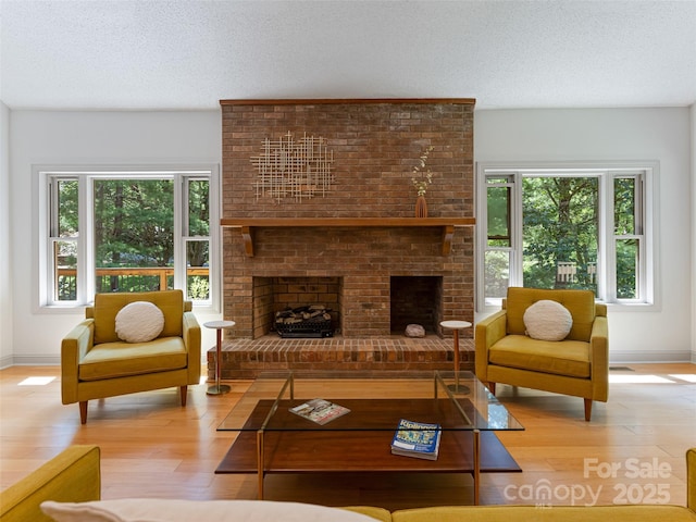 living room featuring a textured ceiling, a fireplace, and wood finished floors