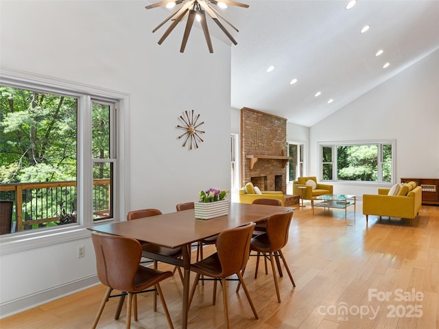 dining area featuring high vaulted ceiling, recessed lighting, a ceiling fan, light wood-type flooring, and a brick fireplace