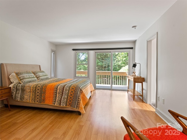 bedroom with access to exterior, light wood-style floors, and baseboards