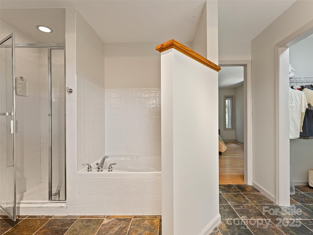 bathroom with a bath, a stall shower, and stone tile flooring