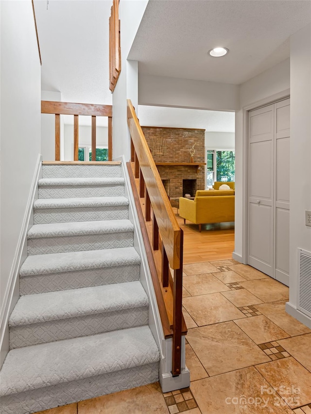 staircase featuring baseboards, a fireplace, visible vents, and recessed lighting