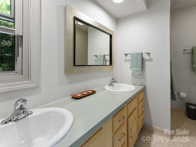 bathroom featuring tile patterned flooring, a sink, a textured ceiling, and double vanity