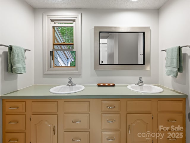 bathroom featuring a sink, a textured ceiling, and double vanity